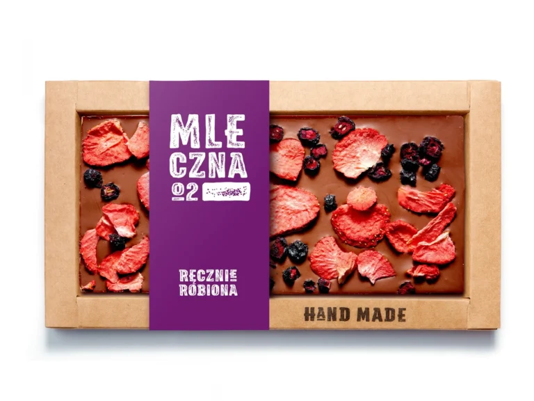 Ręcznie robiona mleczna czekolada z kawałkami truskawek i jagód w ekologicznym opakowaniu.