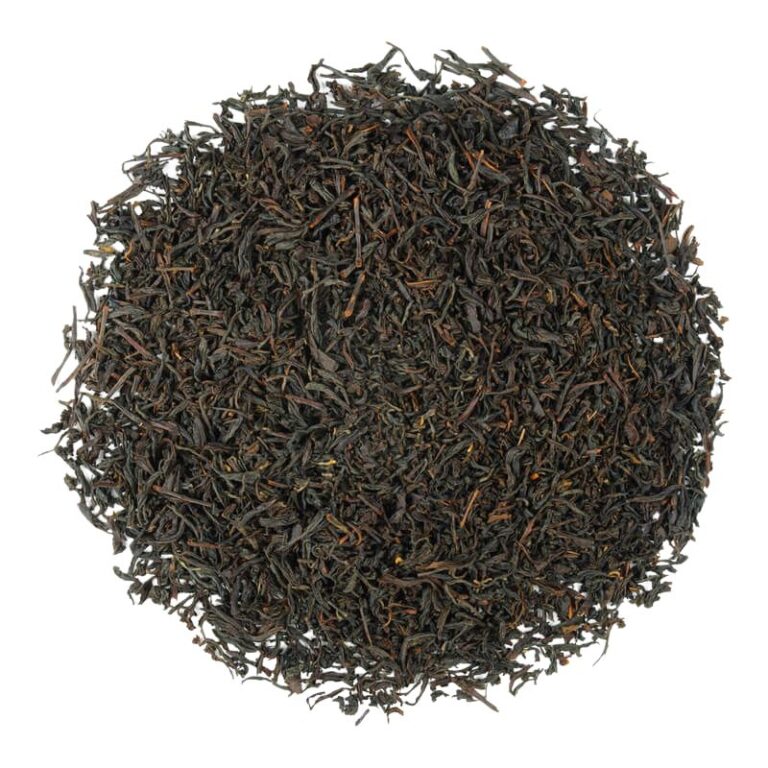 Czarna herbata liściasta ułożona w okrąg na białym tle, gotowa do zaparzenia.