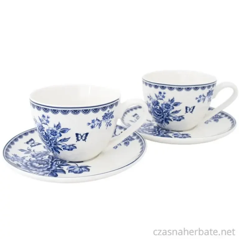 Dwie porcelanowe filiżanki ze spodkami, ozdobione niebieskim kwiatowym wzorem z motylami na białym tle.