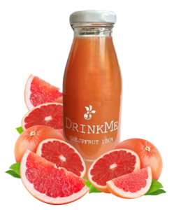 Butelka soku grejpfrutowego otoczona połówkami świeżych grejpfrutów, napój 100% naturalny.