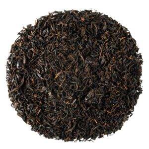 Czarna herbata liściasta w okrągłym układzie, widok z góry na białym tle.