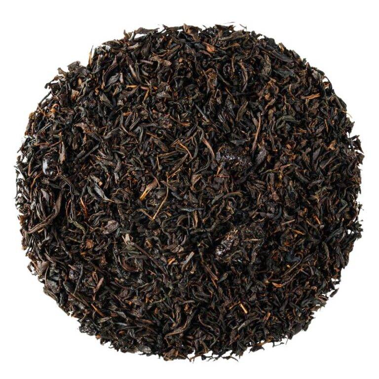 Czarna herbata liściasta w okrągłym układzie, widok z góry na białym tle.
