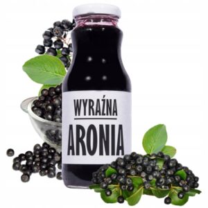 Butelka soku z aronii z napisem Wyraźna Aronia, otoczona świeżymi owocami i liśćmi aronii.