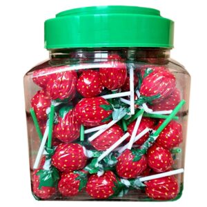 Słoik pełen lizaków w kształcie truskawek w czerwonym opakowaniu, z zielonymi patyczkami, zamknięty zieloną zakrętką.