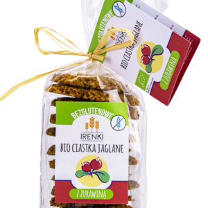 Bezglutenowe bio ciastka jaglane z żurawiną w przezroczystym opakowaniu, ozdobione etykietą i wstążką.
