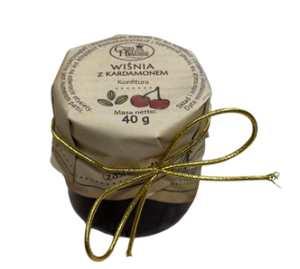 Mały słoik konfitury wiśniowej z kardamonem, ozdobiony złotą kokardą.