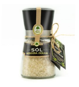 Słoik z solą wędzoną ziołami w młynku, opakowany z zielonymi etykietami i sznurkiem.