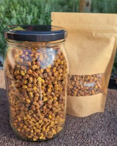 Słoik i worek z pszczelim pyłkiem na tle zieleni, bogatym w składniki odżywcze, idealnym do zdrowej diety i suplementacji.