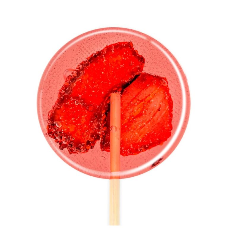 Przezroczysty lizak z kawałkami czerwonych truskawek w środku na białym tle.