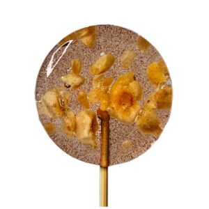 Lizak karmelowy z kawałkami orzechów, na drewnianym patyczku, na białym tle.