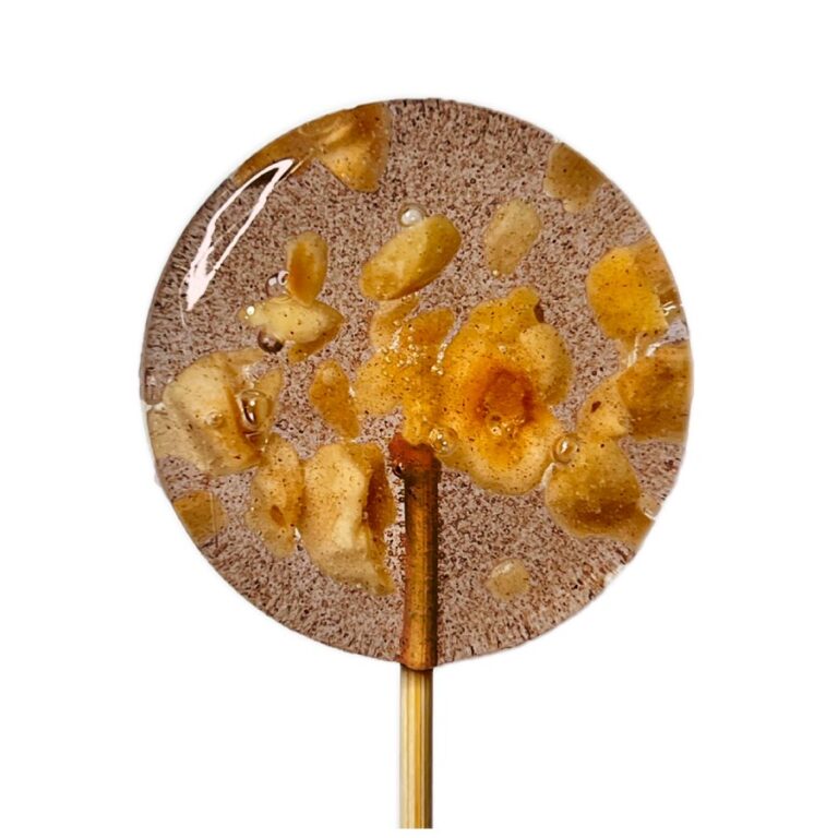 Lizak karmelowy z kawałkami orzechów, na drewnianym patyczku, na białym tle.