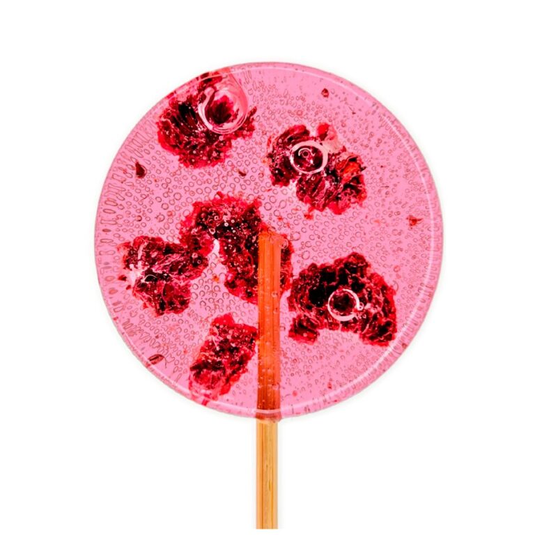 Różowy lizak z owocami osadzonymi w środku, widok od góry na przezroczystą powierzchnię z bąbelkami.